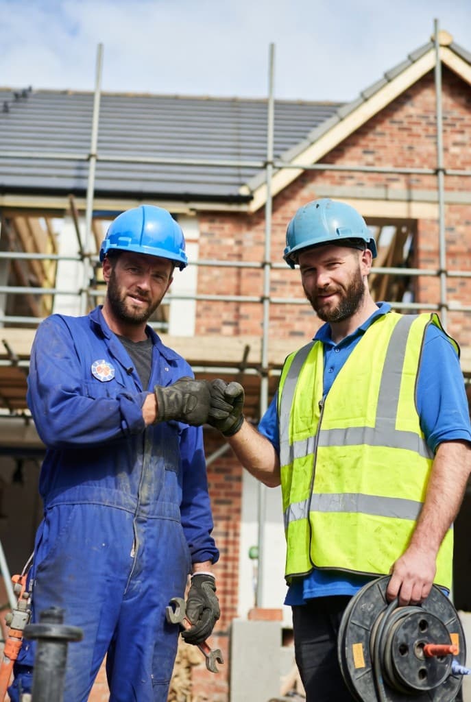 Two construction workers fist bumping on site – professionals celebrating success